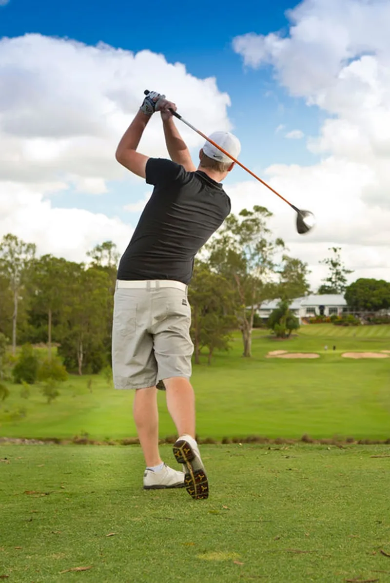 Golfer watching his drive from a full follow-through position on the course