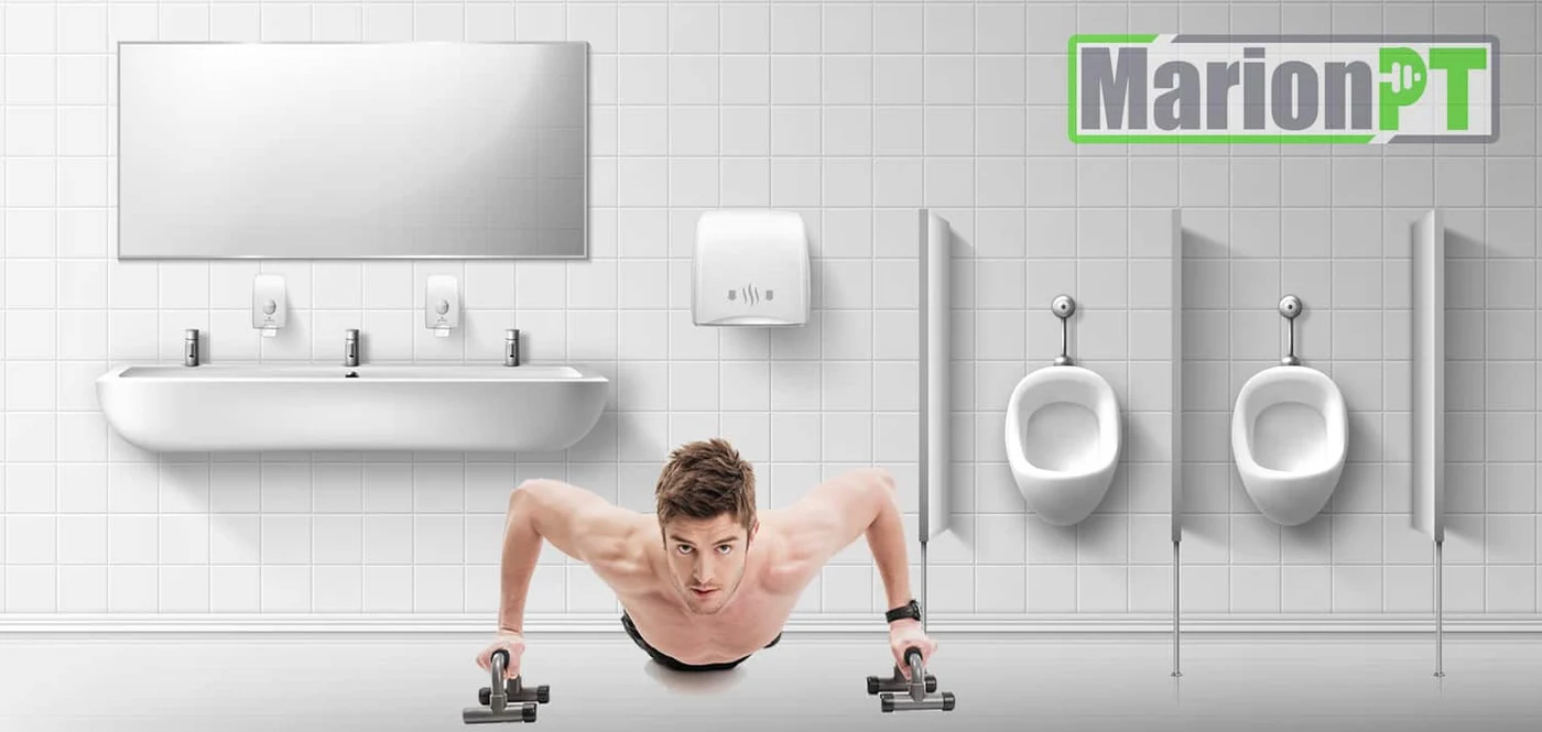 A man doing push-ups on push-up handles in the middle of a tiled public bathroom