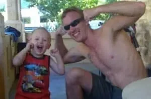 Henk crouching and flexing beside his young son, who is copying the pose