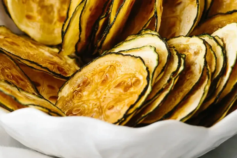 Thin, crisp baked zucchini chips piled in a bowl