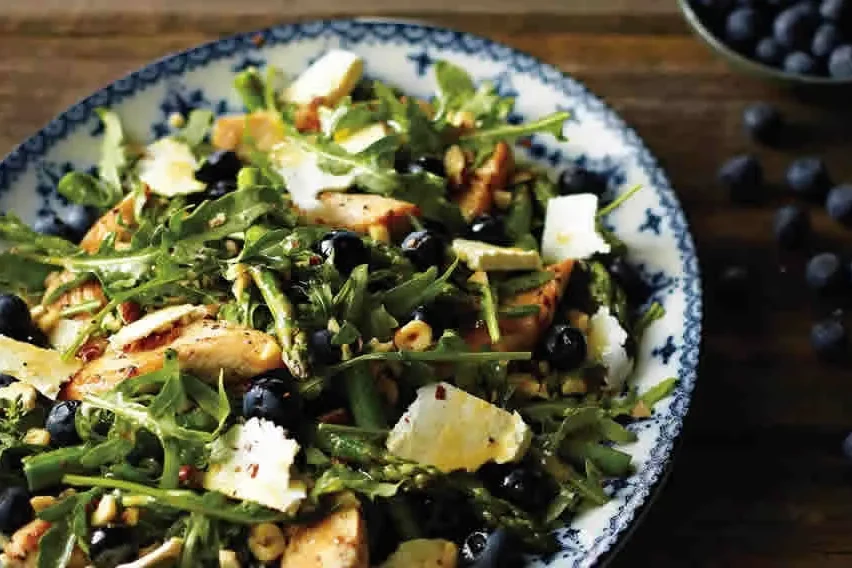 A salad of grilled chicken strips, asparagus, blueberries, rocket and salted ricotta