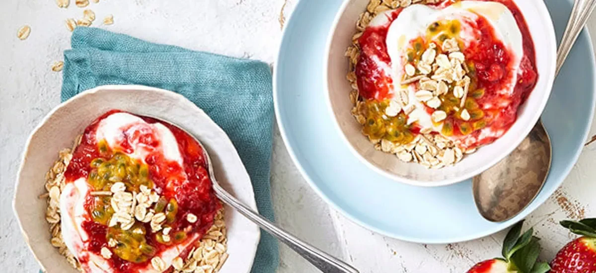 A bowl of muesli layered with mashed strawberries and vanilla yoghurt
