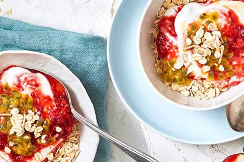 A bowl of muesli layered with mashed strawberries and vanilla yoghurt