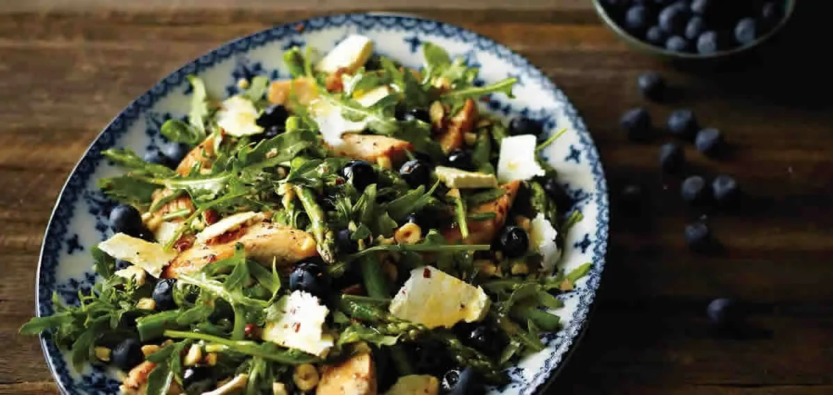 A salad of grilled chicken, asparagus, blueberries and salted ricotta