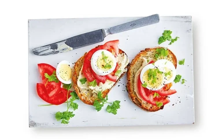 Seeded sourdough topped with hummus, sliced tomato, boiled egg and parsley