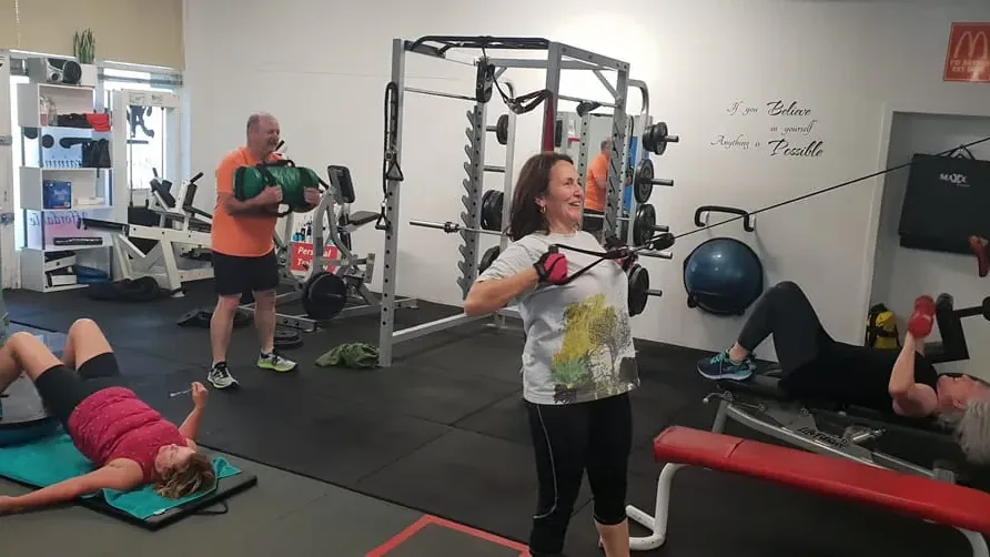 A group training session in progress, with members working on a bosu, a cable machine and a bench