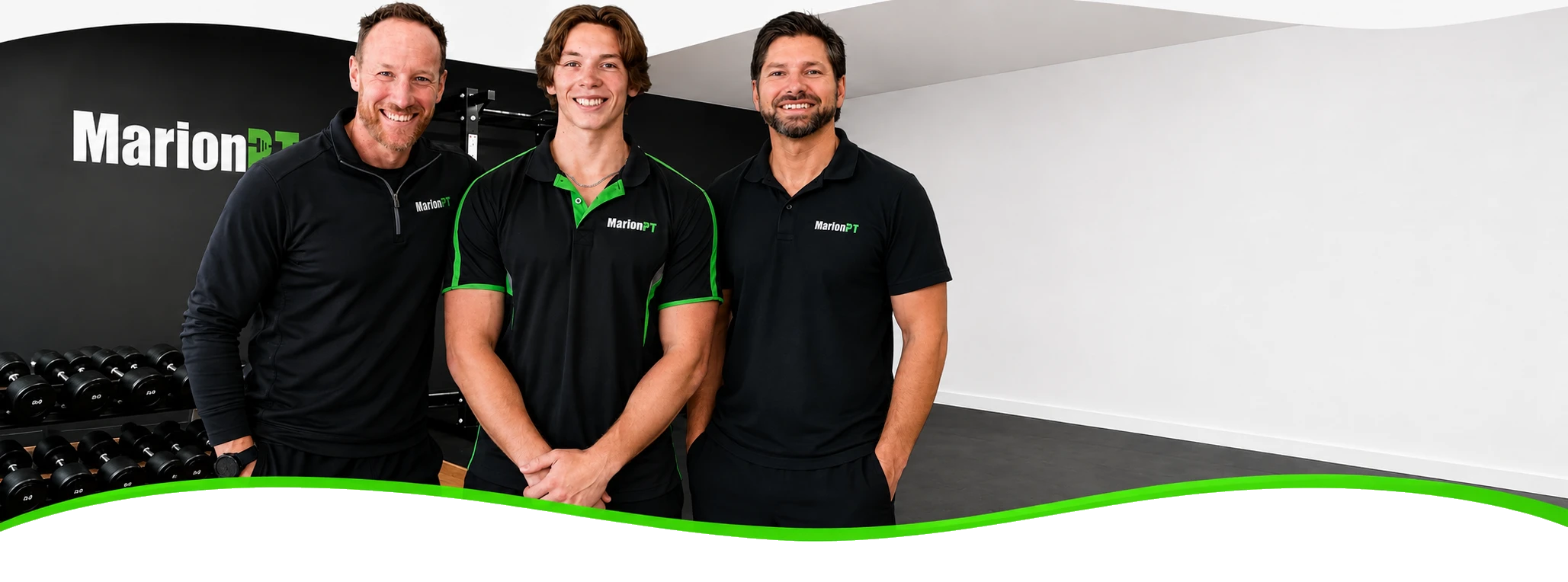 The three MarionPT trainers standing together in the Warradale studio in branded shirts, in front of the dumbbell rack and the MarionPT wall logo