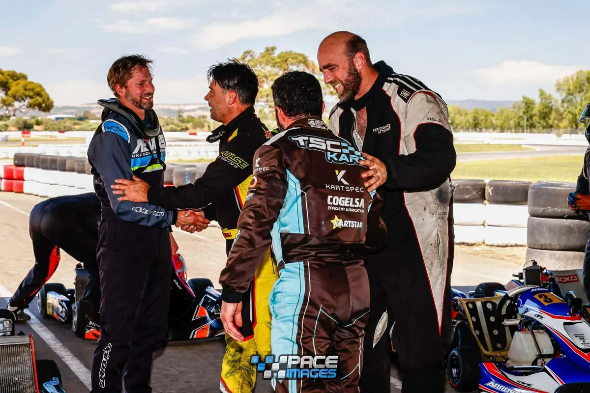 Duran, at left in racing overalls, shaking hands with other drivers in the pits after a kart race