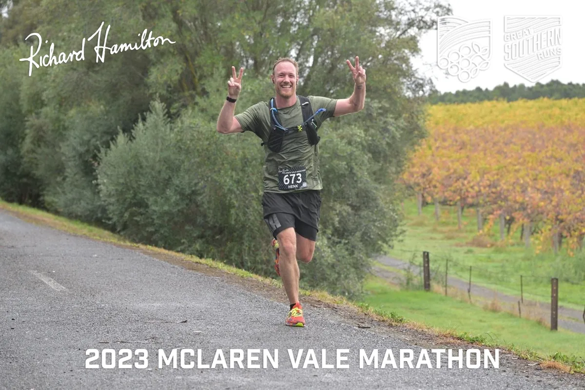 Henk running the 2023 McLaren Vale half marathon, both arms raised, wearing race number 673